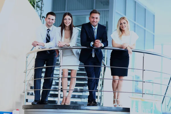 Portrait of positive business group standing on stairs of modern office — Stock Photo, Image