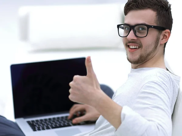 Modern young sitting in front of the open laptop and showing thumb up — Stock Photo, Image