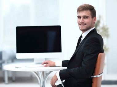 Masada oturan ve kameraya bakarak başarılı iş adamı.
