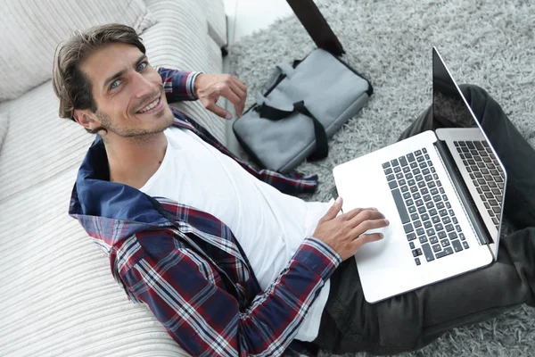 Uomo d'affari con computer portatile seduto su tappeto in soggiorno . — Foto Stock