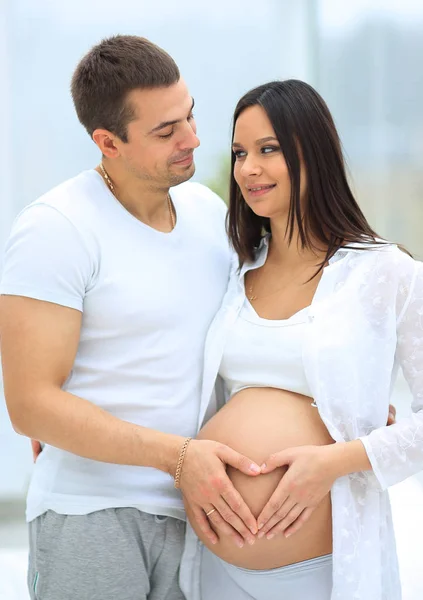 Marido y mujer embarazada con las manos dobladas en forma de corazón en la barriga —  Fotos de Stock