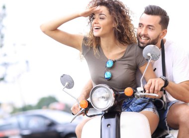 Güzel genç bir çift bir scooter sürme sırasında gülümsüyor