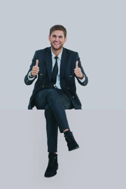 Beyaz bir üstünde otururken yakışıklı genç iş adamı.