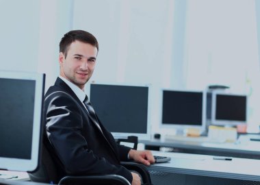 Genç işadamı ofiste çalışıyor, masada oturuyor.