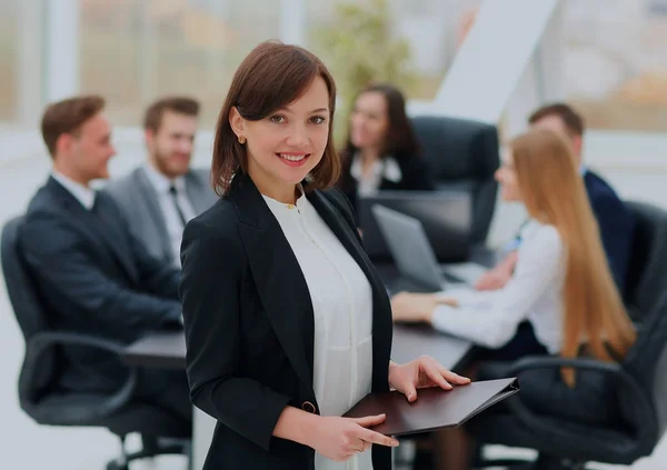 Mulher de negócios bem sucedida de pé com seu pessoal no fundo no escritório . — Fotografia de Stock