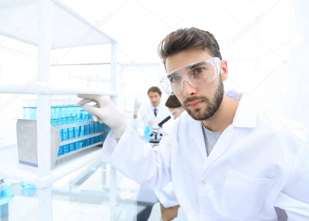 Young male scientist looking at a sample in a test tube side vie