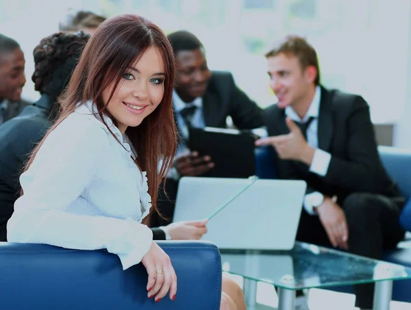 Nahaufnahme einer hübschen jungen Geschäftsfrau, die bei einem Treffen mit ihren Kollegen im Hintergrund lächelt. — Stockfoto