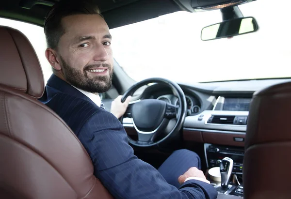 businessman sitting at the wheel of a prestigious car
