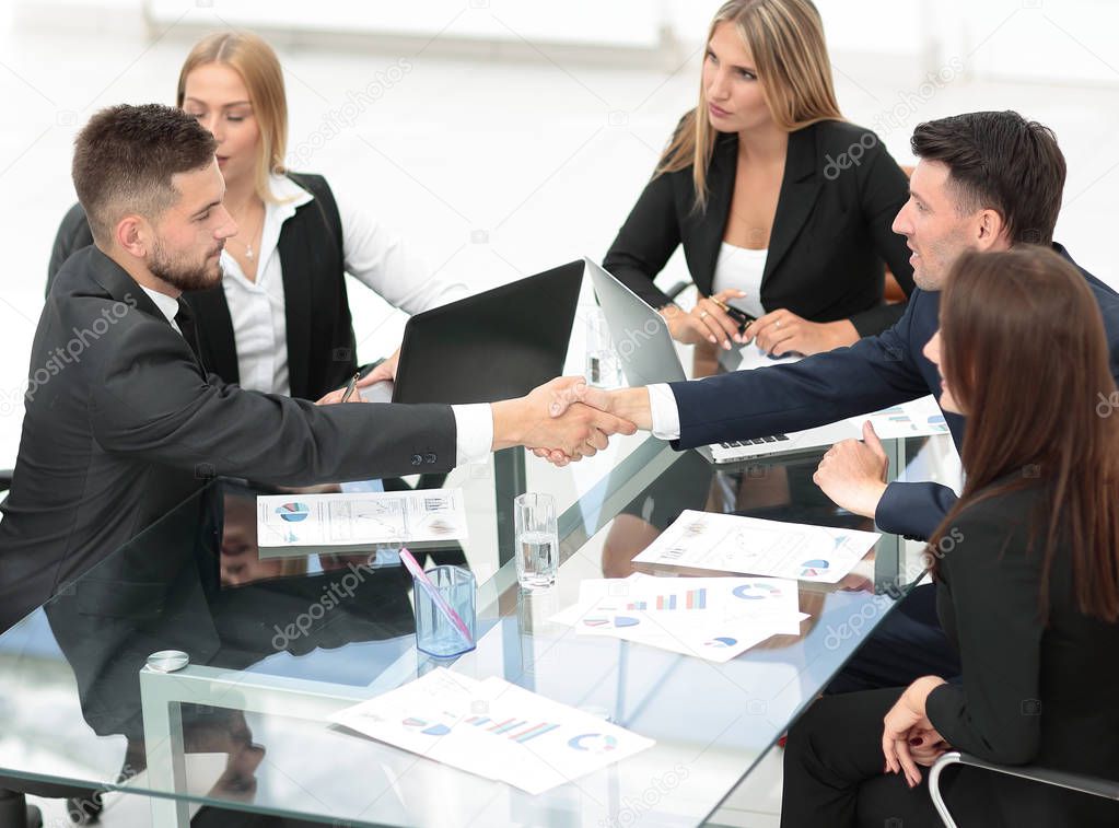 handshake of business partners sitting at your Desk