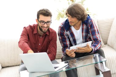 dizüstü ve tablet kanepede oturan çalışan iki genç adam