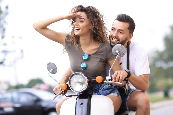 Belo jovem casal está sorrindo enquanto monta uma scooter — Fotografia de Stock