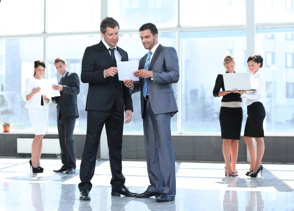 I dipendenti discutono i documenti di lavoro, in piedi nella hall — Foto Stock