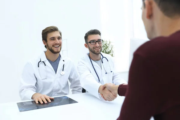 Sorridente medico presso la clinica dando una stretta di mano al suo paziente — Foto Stock