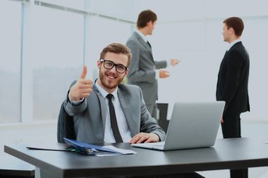 yakışıklı genç iş adamı office toplantısında arka planda insanlarla. başparmak gösterilmesini.