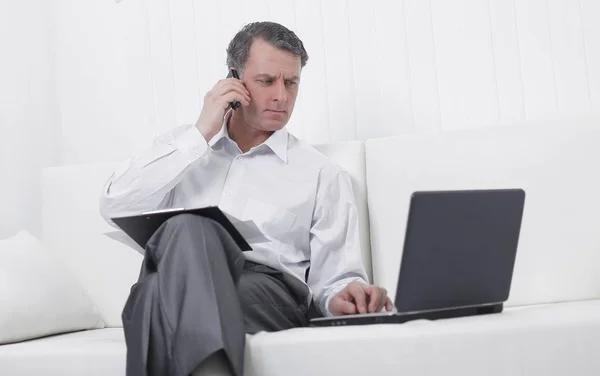 Homem de negócios trabalhando com laptop e falando em um telefone celular — Fotografia de Stock