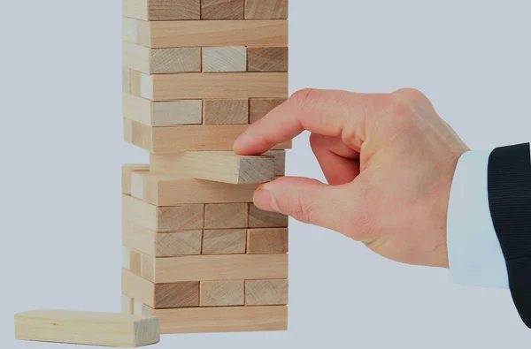 Башня из деревянных блоков и человек руки взять один блок. — стоковое фото