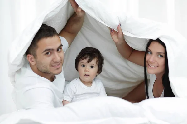 Famílias com crianças na cama sob um cobertor — Fotografia de Stock