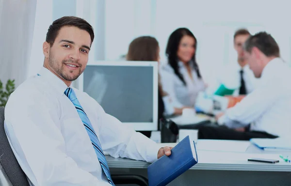 Zufriedener Geschäftsmann mit Kollegen bei einer Konferenz im Hintergrund. — Stockfoto