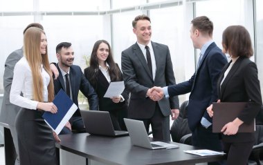 Ofisteki bir toplantıda iş ortakları tokalaşıyor.