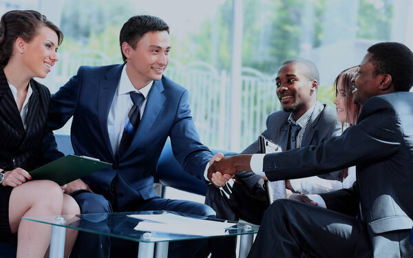 Two business man shaking hands with his team in office.