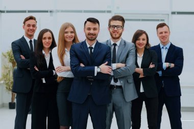 Smiling and confident business team standing in front of a bright window. clipart