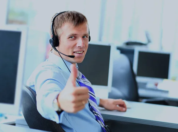 Χαρούμενος νεαρός άνδρας που εργάζονται σε callcenter, χρησιμοποιώντας ακουστικό. — Φωτογραφία Αρχείου