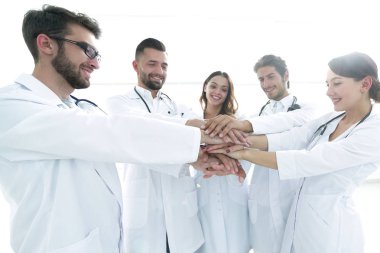 Doktorlar ve hemşireler tıbbi bir ekipte el ele tutuşuyorlar.