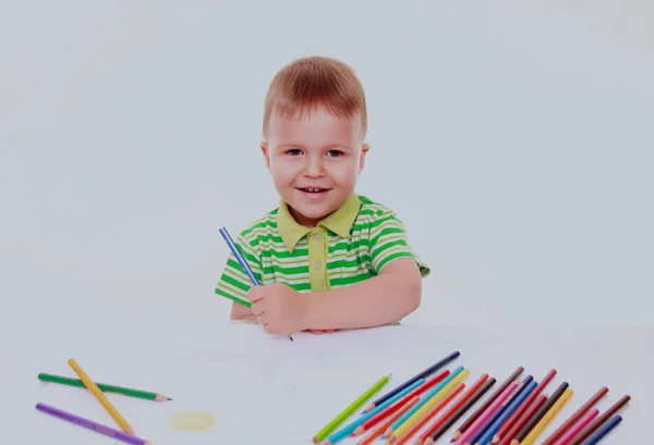 Petit garçon inspiré à la table dessiner avec des crayons, isolé sur blanc — Photo