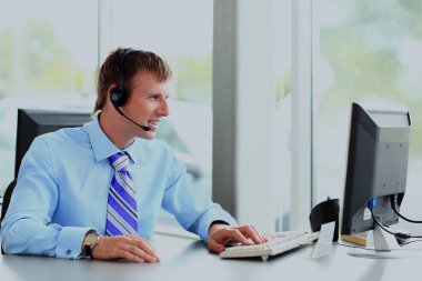 kulaklık kullanarak callcenter çalışma mutlu genç adam.