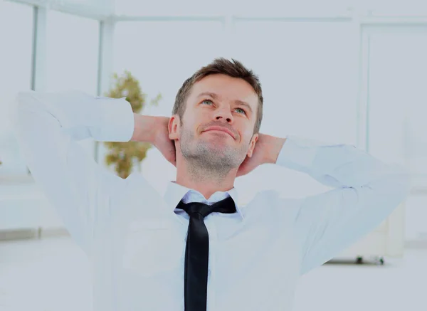 Joven hombre de negocios soñando con las manos detrás de la cabeza sentado en la oficina . — Foto de Stock