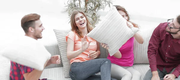 Fröhliche Freunde, die mit den Kissen auf der Couch spielen — Stockfoto