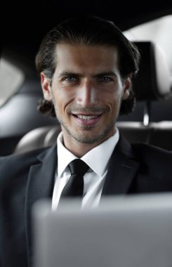 bir arabanın arka koltuğunda oturan adam onun laptop kullanma