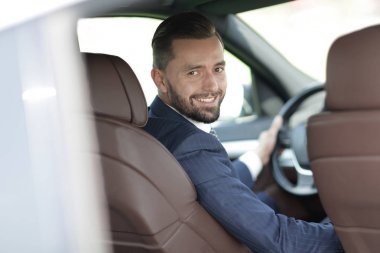 bir araba direksiyon başında oturan ve kameraya bakarak işadamı