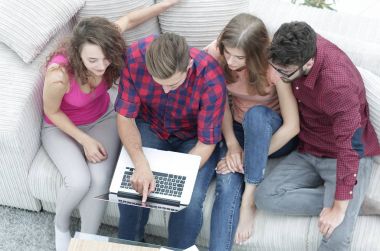 kanepede oturan dizüstü bilgisayar ile arkadaş grubu.