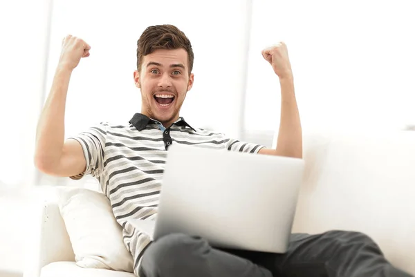 Hombre feliz con el ordenador portátil sentado en el sofá — Foto de Stock