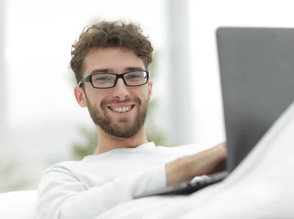 Smiling man using laptop lying on bed — Stock Photo, Image