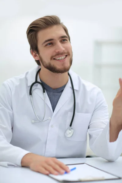 Médecin souriant assis derrière un bureau — Photo