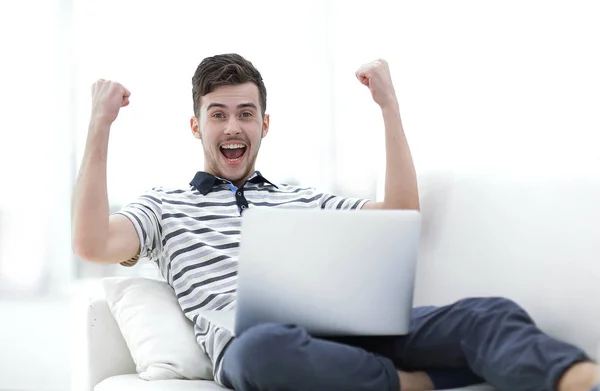 Hombre feliz con el ordenador portátil sentado en el sofá —  Fotos de Stock