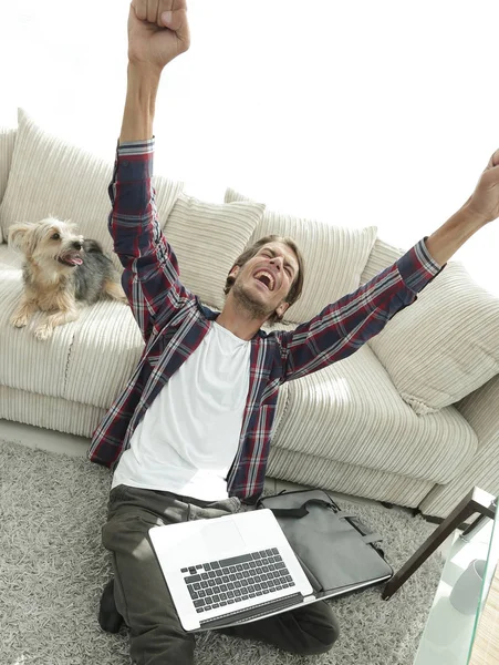 Glücklicher Kerl mit Laptop jubelt im geräumigen Wohnzimmer. — Stockfoto