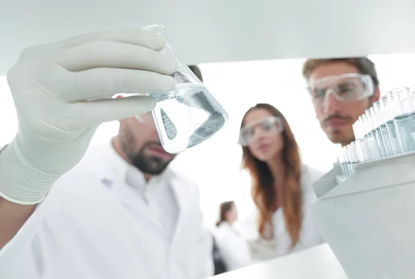 Closeup.a groep van wetenschappers bestuderen van de vloeistof in de glazen buis — Stockfoto