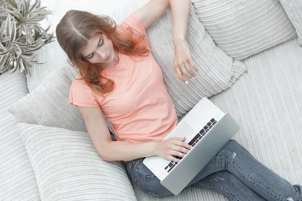 Menina estudante com laptop sentado descansando no sofá . — Fotografia de Stock