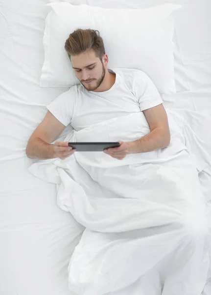 Homem bonito lendo no tablet digital no quarto — Fotografia de Stock