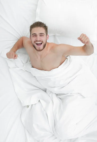 Ovanifrån. lycklig man vakna upp i en bekväm säng — Stockfoto