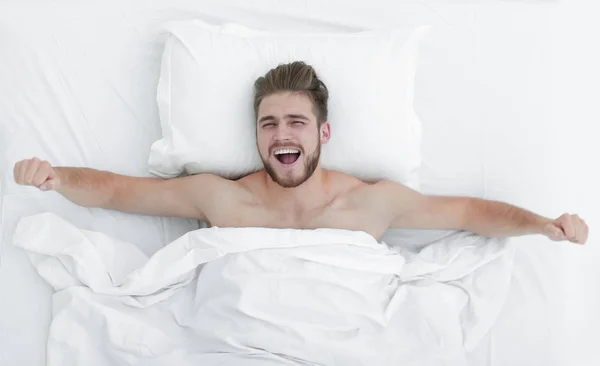 Vista superior. homem feliz acordando em uma cama confortável — Fotografia de Stock