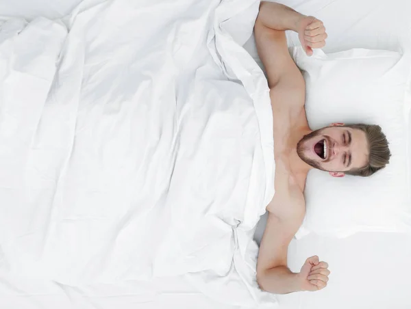 Vista superior. hombre feliz despertando en una cama cómoda — Foto de Stock