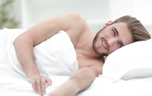 Glücklicher Mann, der in einem bequemen Bett einschläft — Stockfoto