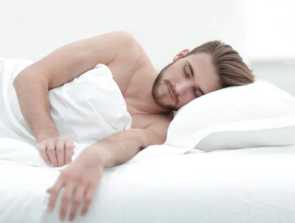 Hombre sonriente durmiendo en una cama cómoda . — Foto de Stock