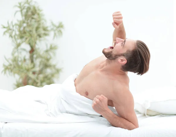 Successful man yawns, lying in the bedroom — Stock Photo, Image