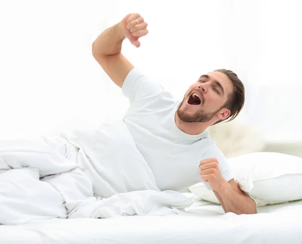 Handsome man waking up in a cosy bedroom. — Stock Photo, Image