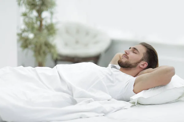 Уставший мужчина отдыхает на удобной кровати — стоковое фото